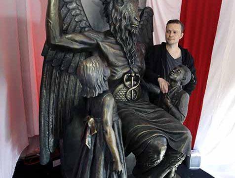 In this Oct. 24, 2016 photo, Lucien Greaves stands next to a 9-foot statue of the goat-headed idol Baphomet at the recently opened international headquarters of the Satanic Temple in Salem, Mass. The Satanic Temple is waging religious battles along a variety of fronts nationwide, and its co-founder says it's just getting started. Greaves says the temple hopes to ensure Satanists "have a place in the world" and that "evangelical theocrats" don't monopolize the religious freedom debate. (AP Photo/Elise Amendola)